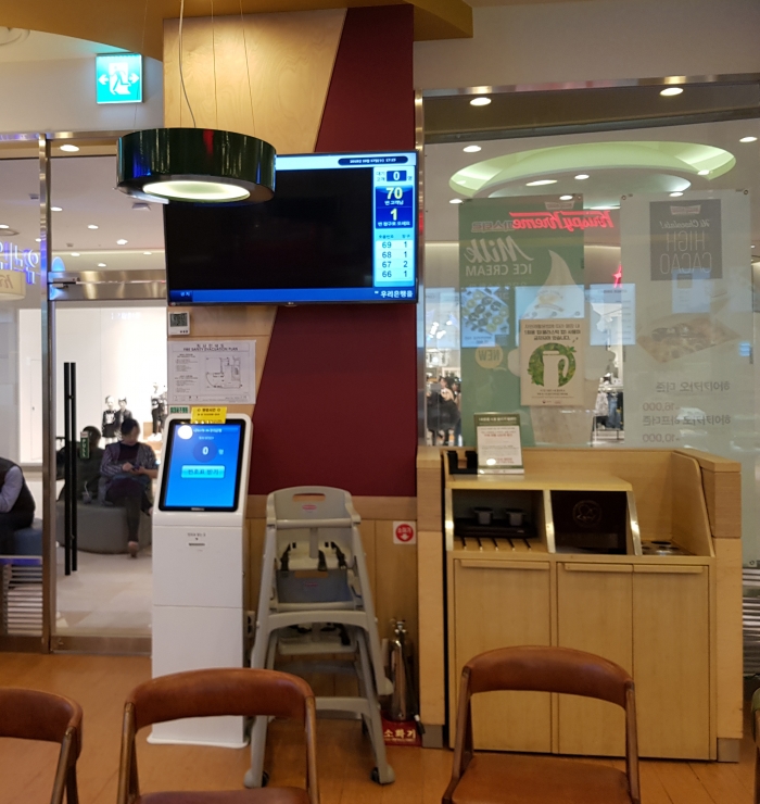 나란히 놓여있는 은행 번호표 기계와 도넛 매장 음식물 정리함.