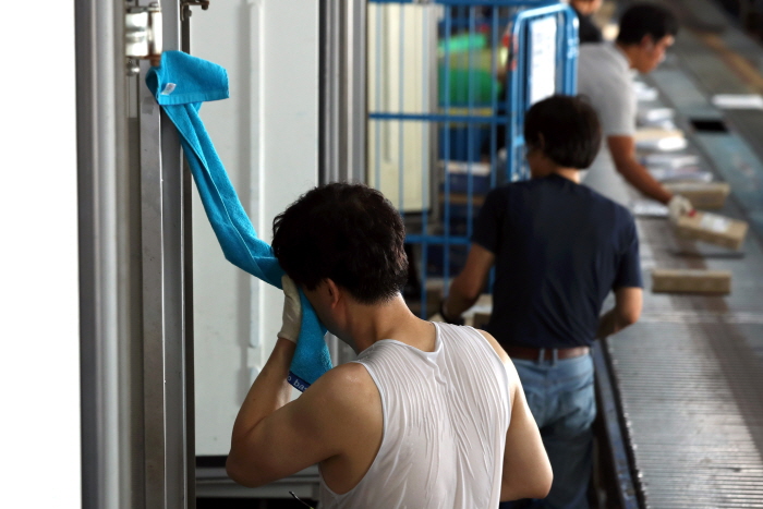 2020년 8월 17일 서울 전역에 폭염경보가 발효된 가운데 서울 시내 한 택배 물류센터에서 한 종사자가 땀을 닦고 있다. 뉴시스.