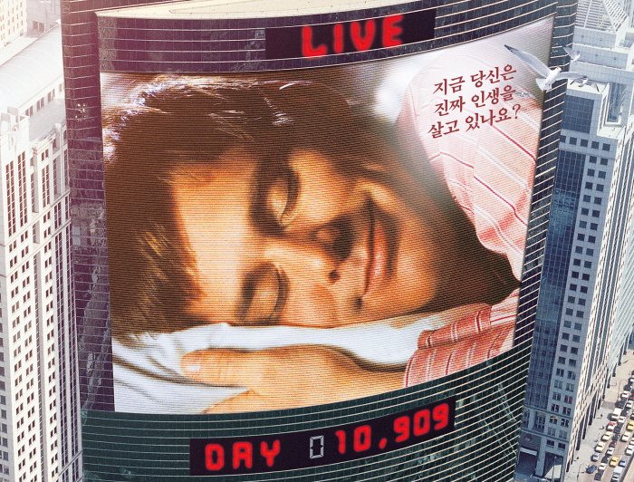 라이브 방송 시작 1만909일째. 영화 '트루먼쇼' 포스터에 실린 대형 빌딩 샤이니지 전광판 모습은 이 영화의 기괴한 설정을 한 눈에 보여준다. 물론 그 기괴함이 지금은 일상적인 시대가 됐지만...