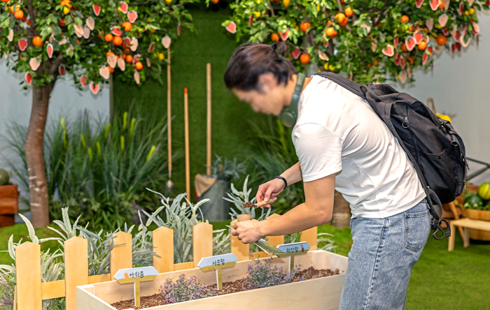 한 관람객이 2단계인 '감정 인기하기' 공간에서 다양한 감정 네임택이 적힌 3가지 감정을 선택해 화분에 흙을 담고 있다. 사진=SK텔레콤 제공.