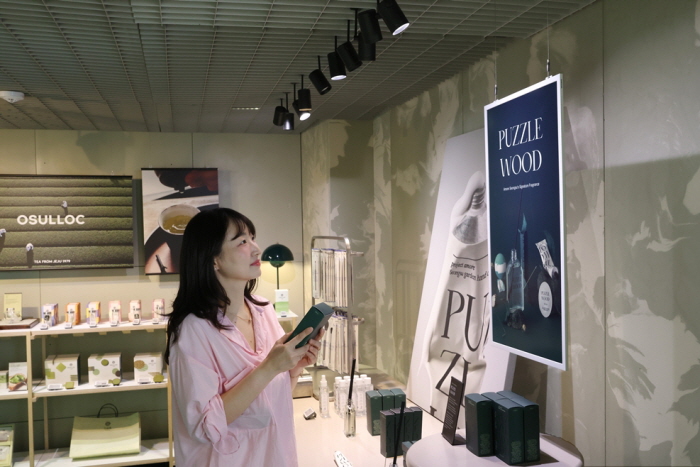 아모레성수 굿즈존에서 삼성 컬러 이페이퍼에 표시된 내용을 살펴보는 방문객